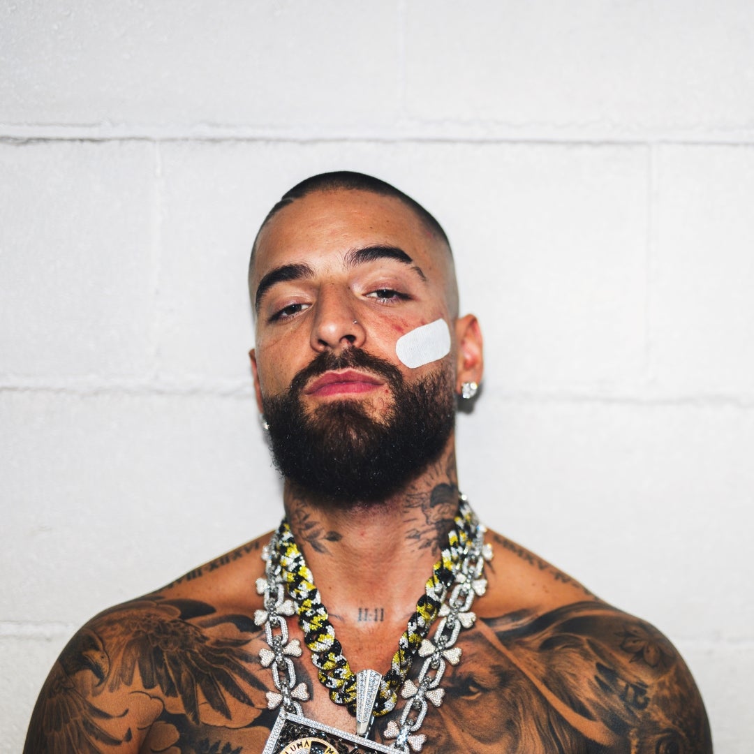 Close-up portrait of Maluma against a white brick wall