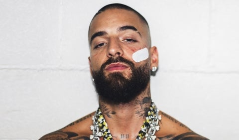 Close-up portrait of Maluma against a white brick wall