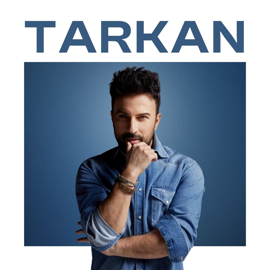 Promotional image of Tarkan against a blue background. He is wearing a denim shirt with rolled-up sleeves and bracelets on his wrist. He poses with a thoughtful expression, resting his chin on his hand. His name "TARKAN" is displayed in bold white capital letters.